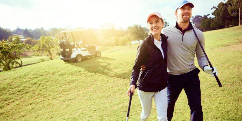 Ein Paar gemeinsam sich umarmend auf dem Golfplatz