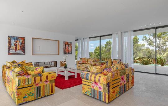 Neubauvilla der Extraklasse in Nova Santa Ponsa - Wohnbereich mit Kamin und Zugang zur Terrasse